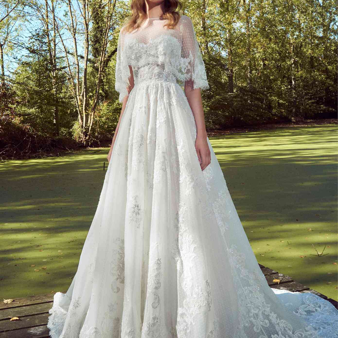 模特在无肩带的甜心点薄纱公主礼服与珠蕾丝刺绣和点薄纱花边与睫毛花边装饰capelet