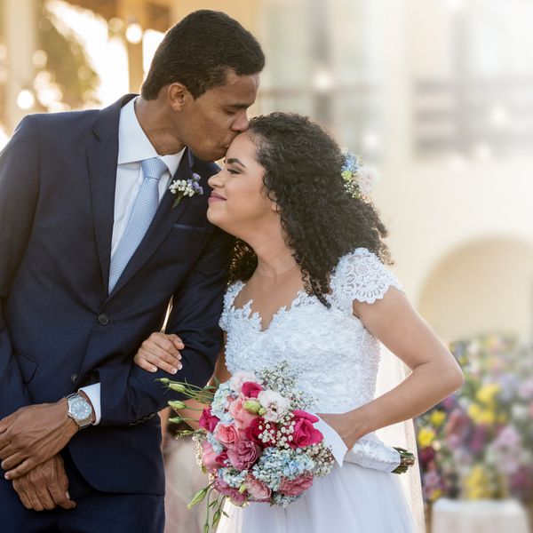 穿衣服的一个人亲吻拿着花束的新娘褂子的一个妇女在一个室外婚礼“class=