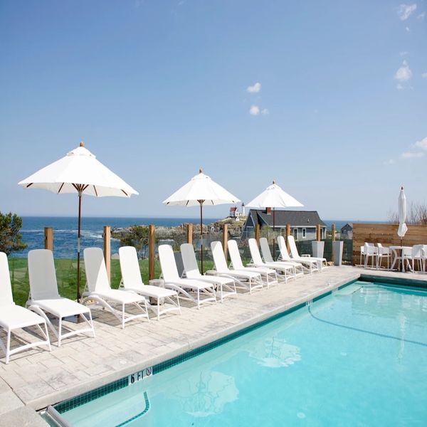 在阳光明媚的日子里，有白色沙滩椅的湖边泳池