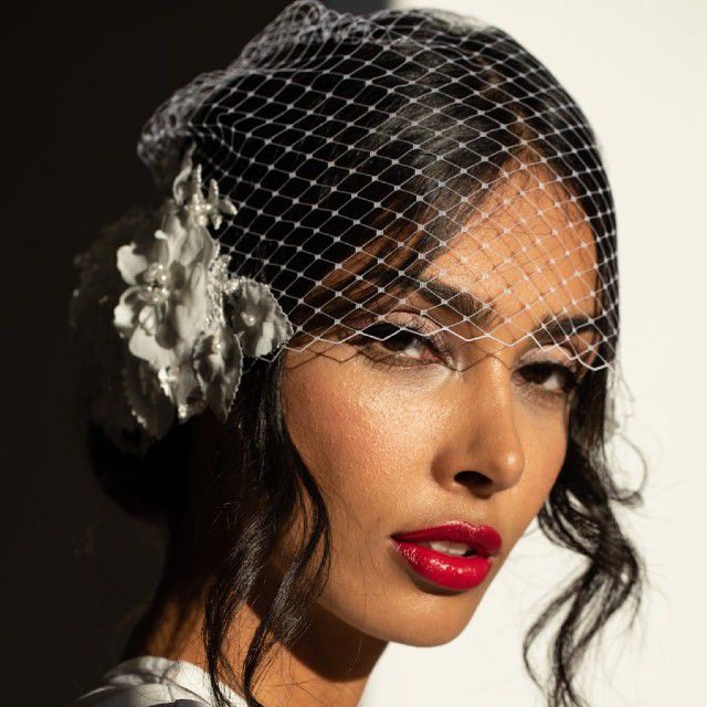 有红色唇膏和鸟笼面纱的新娘与花