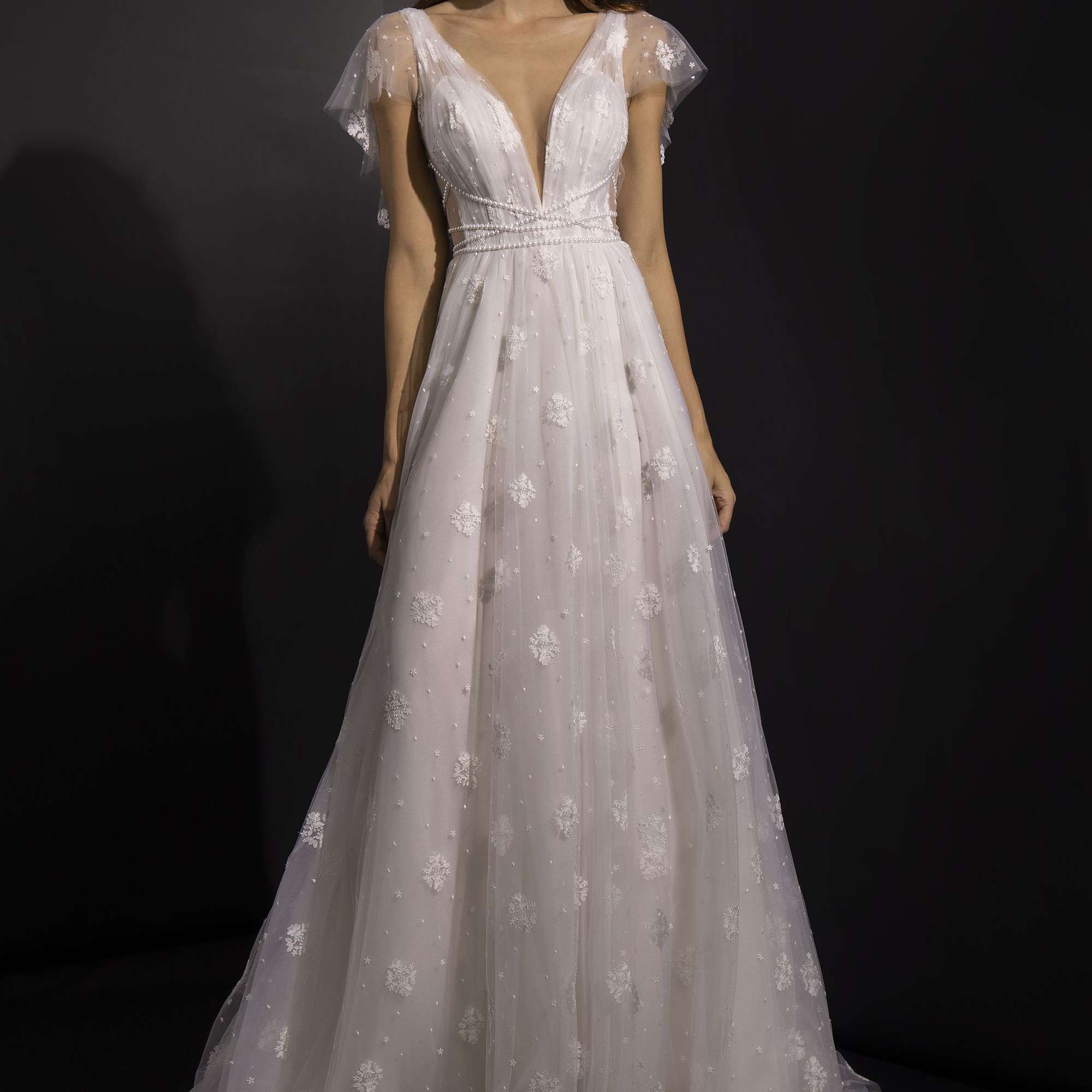 模特身着v领a字裙，薄纱飘动的袖子和蕾丝装饰