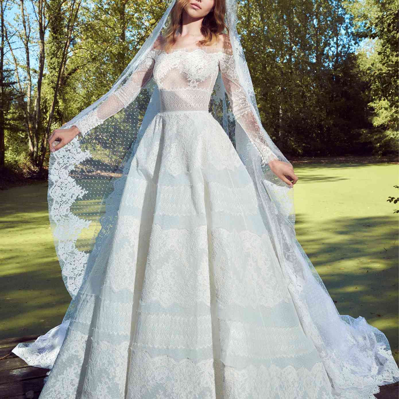 模特在露肩长袖点薄纱舞会礼服与花边刺绣与相配的面纱