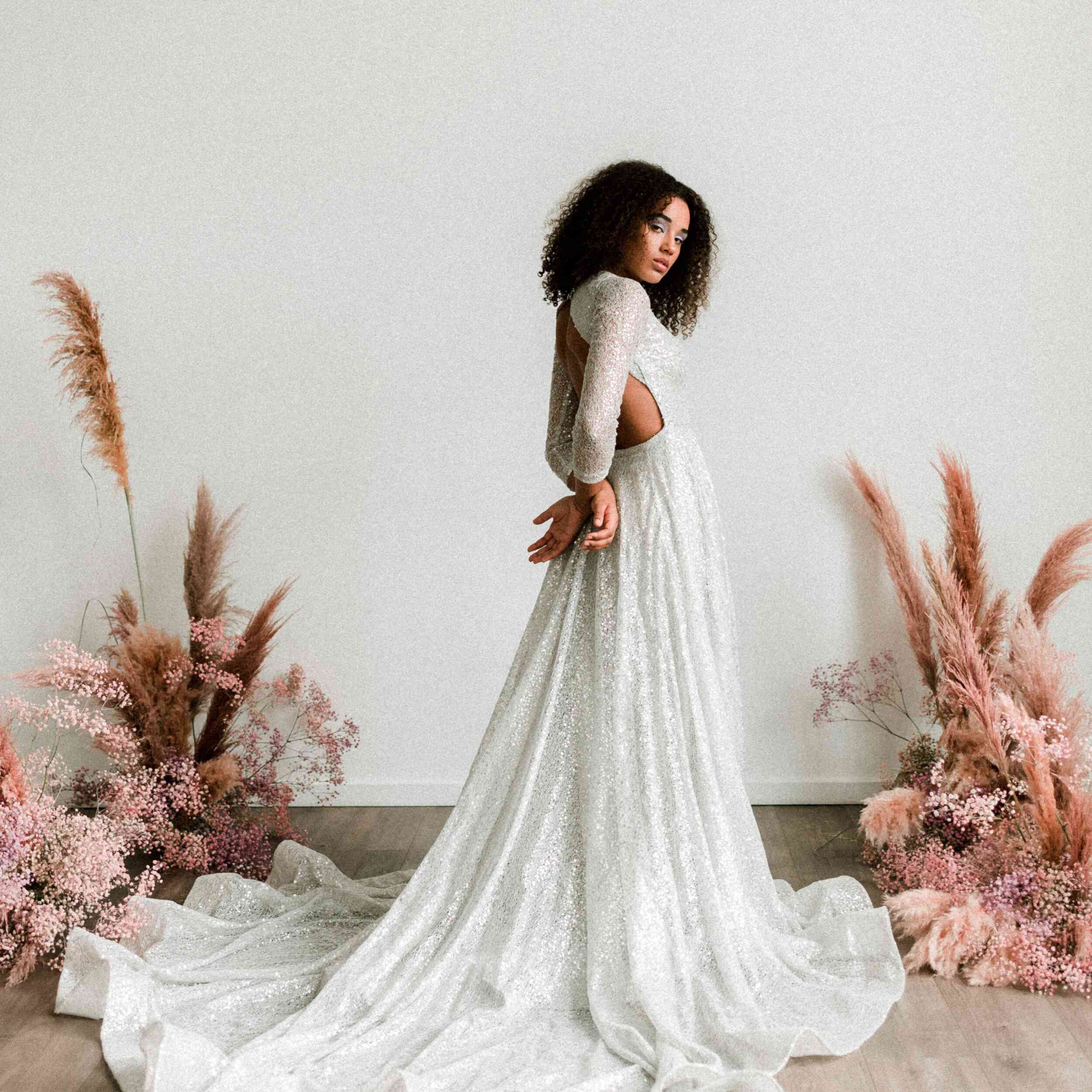 型号站在一边的银色亮片礼服用双手抚摸她的背部背后