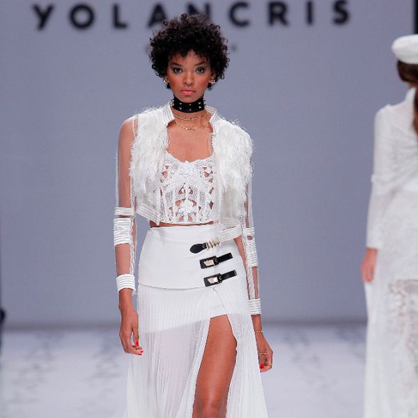 模型与钩针刺绣和3D鲜花和绉褶和乔其纱裙具有高狭缝和黑色和金色扣细节在一侧的紧身衣顶部，穿带条纹的透明轰炸机夹克