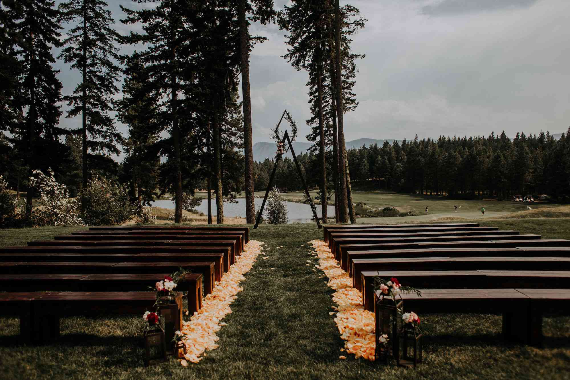 仪式上，长椅和明亮的珊瑚花瓣排列在走廊上，形成一个湖前的三角形拱门