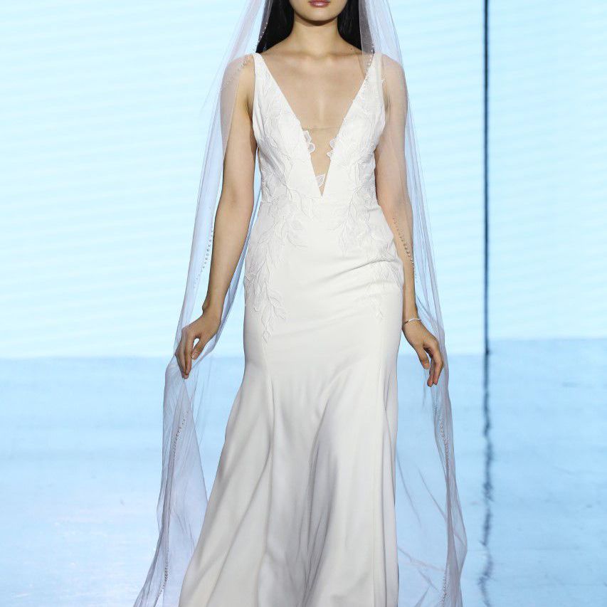 模特在t台上的无袖婚纱与低领和花边贴花