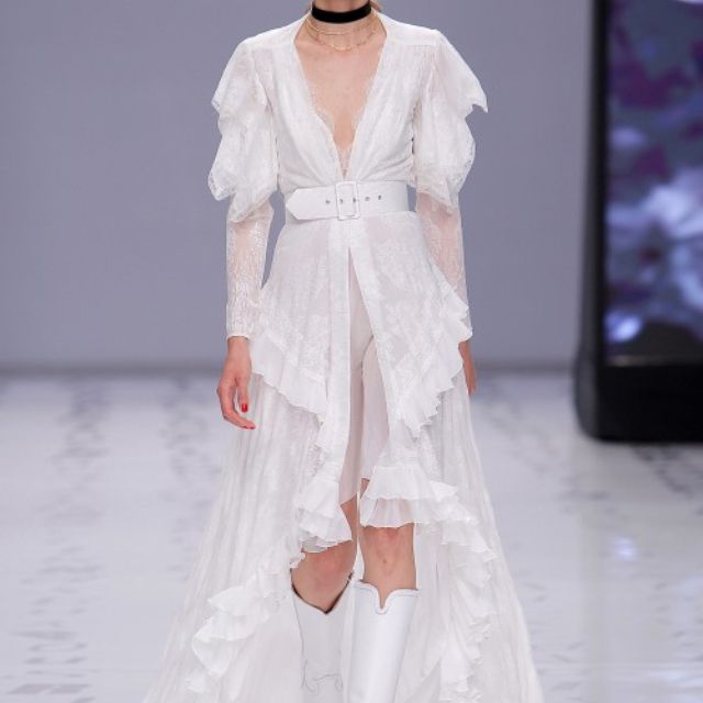 模特身着雪纺连衣裙，绣有乔其纱荷叶边和袖子，饰有chantilly蕾丝，深V领、宽腰带和不对称高低裙