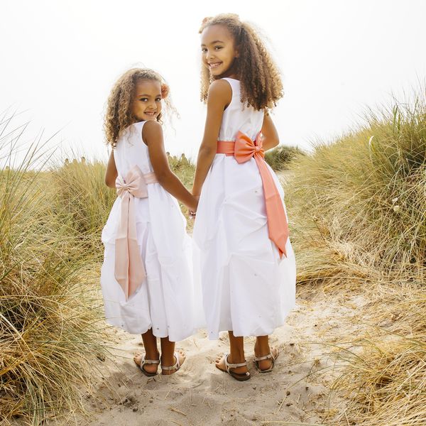 在一场海滩婚礼上，两个年轻的女孩担任初级伴娘