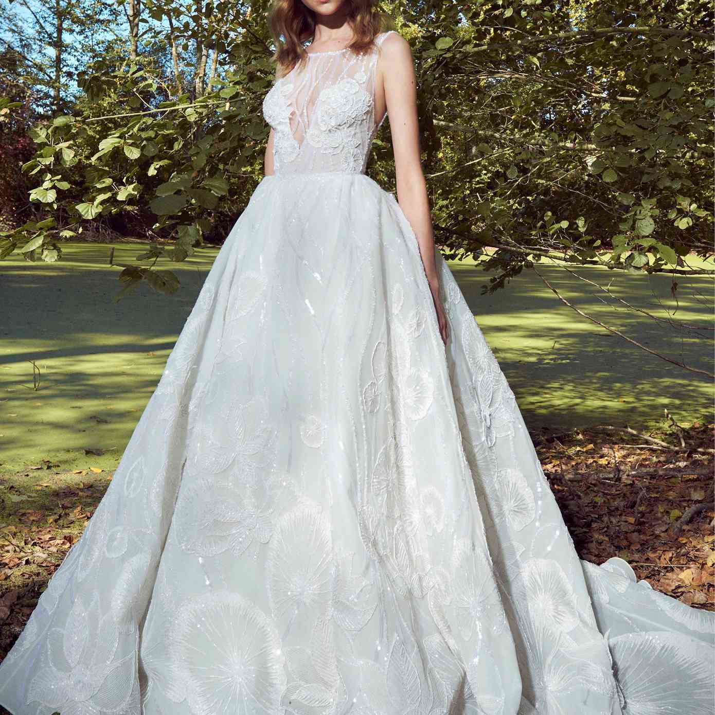 模特穿着一件无袖的舞会礼服，领口有串珠错觉，全身有亮片和贴花的串珠花卉刺绣