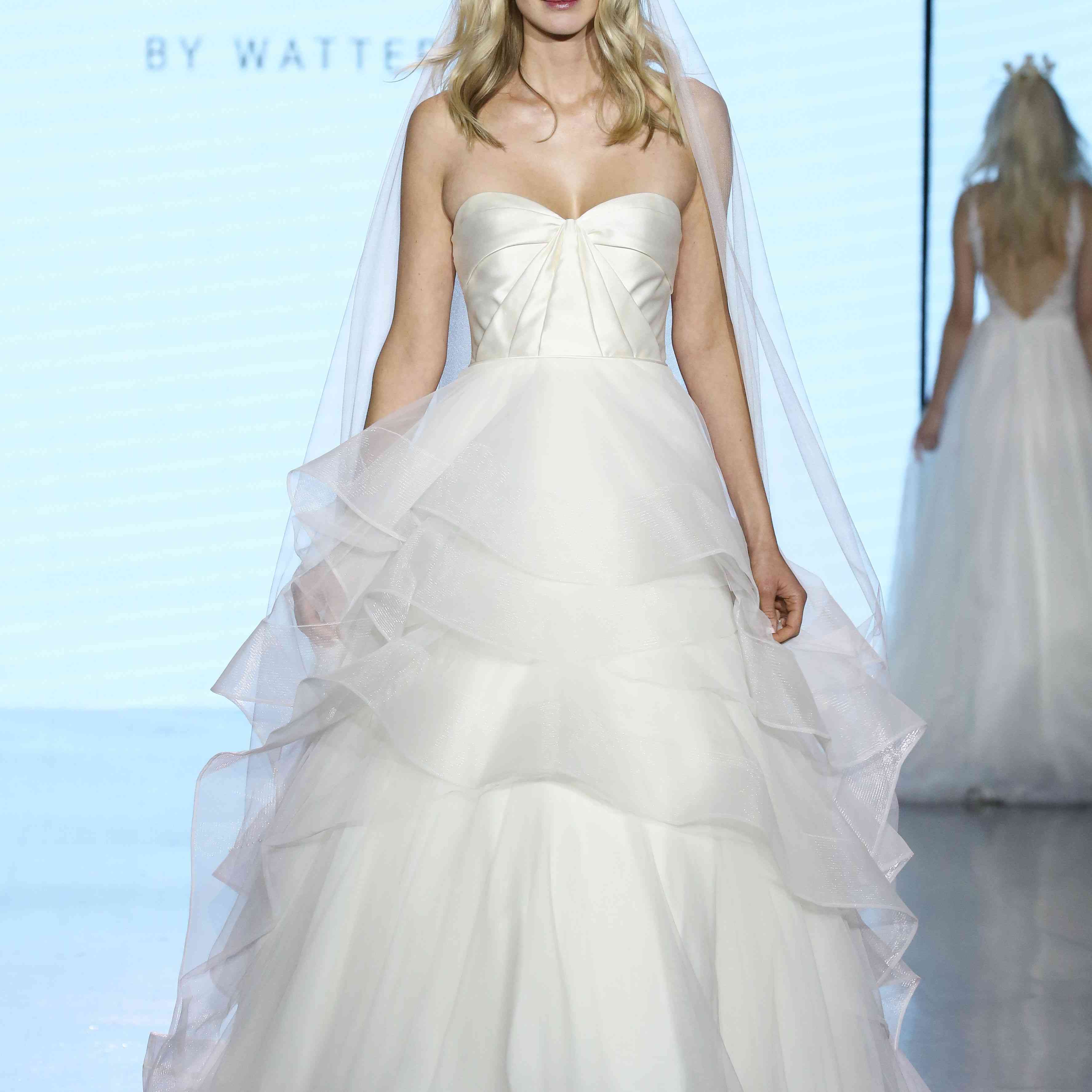 无肩带的型号的模型，带有皱纹的缎面胸衣和一个多层欧耳衬裙