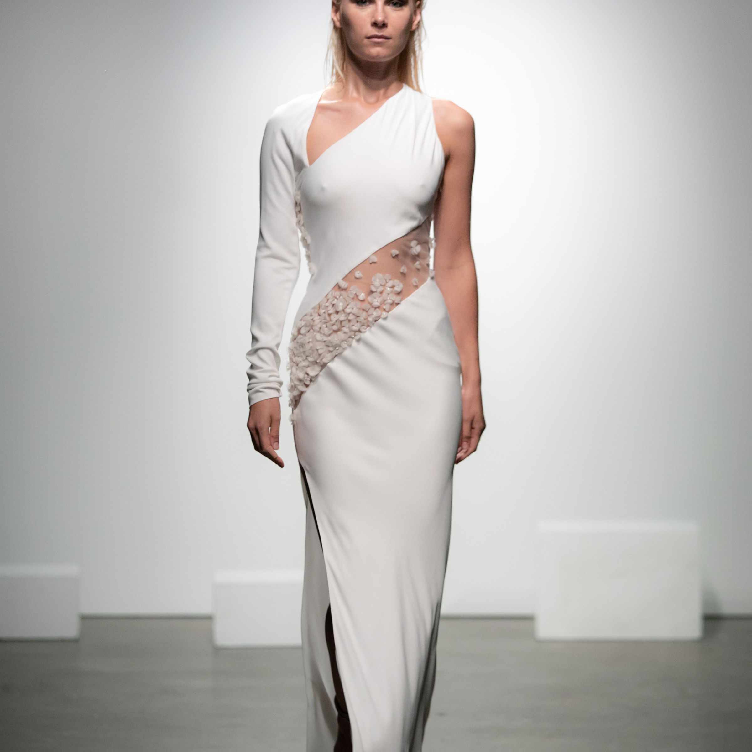 模特身穿一袖不对称绉绸连衣裙，上身绣有薄纱丝带