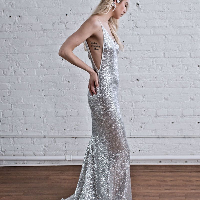 Model in silver sequin dress facing to the right with hands on lower back