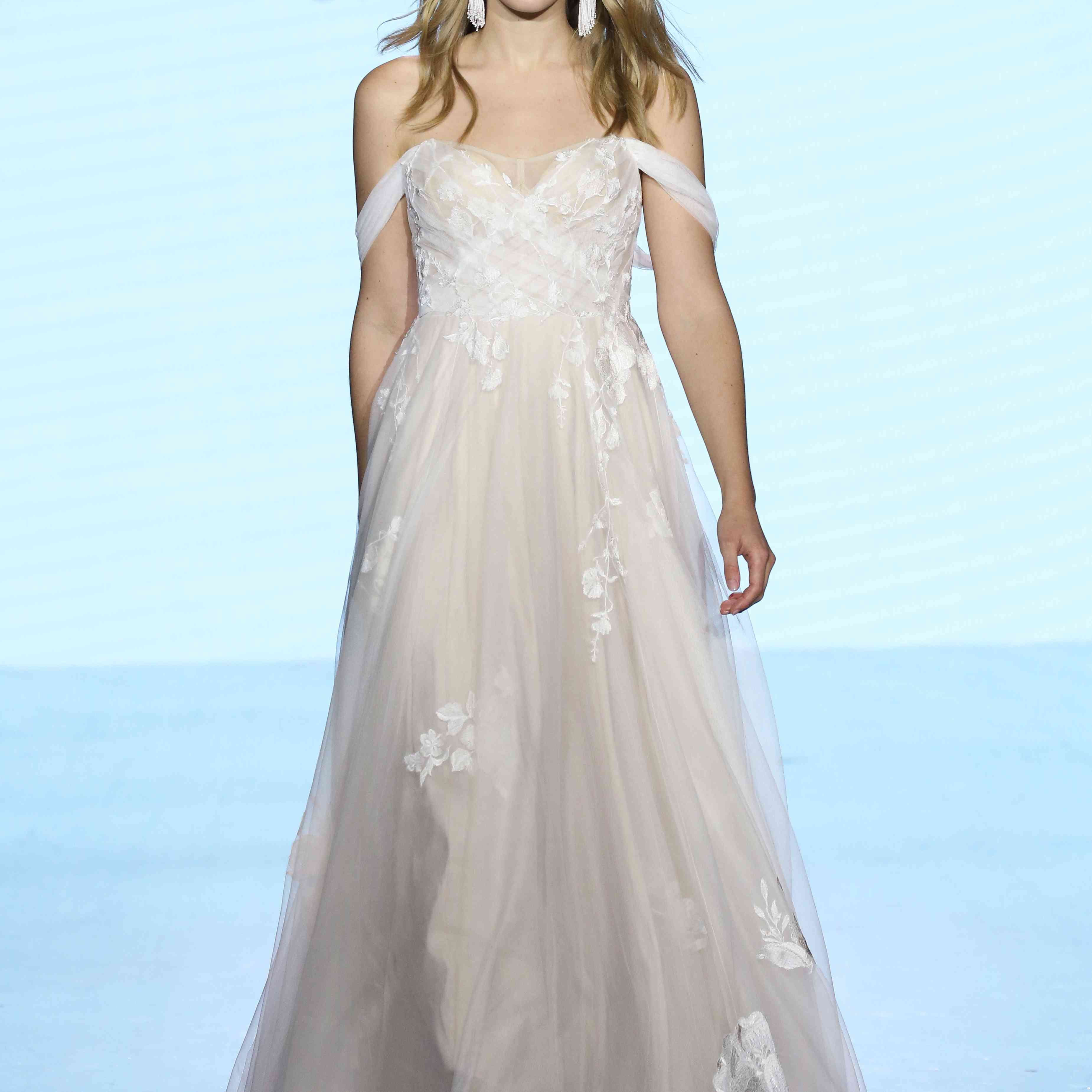 模特在露肩薄纱与花卉贴花a字婚纱