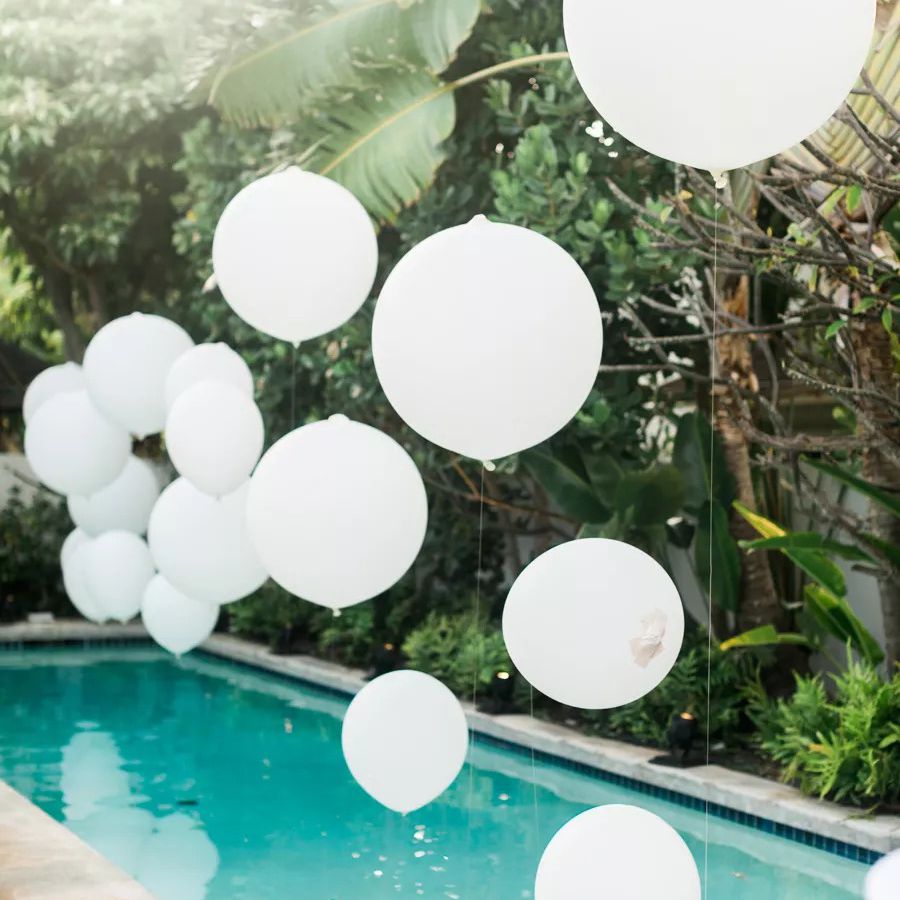 白色的气球在游泳池上空飘浮