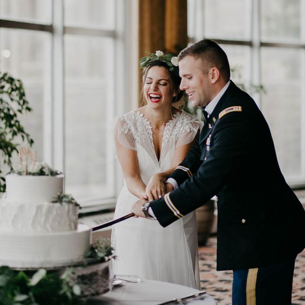 切开与军事军刀的新娘和军事新郎他们的蛋糕