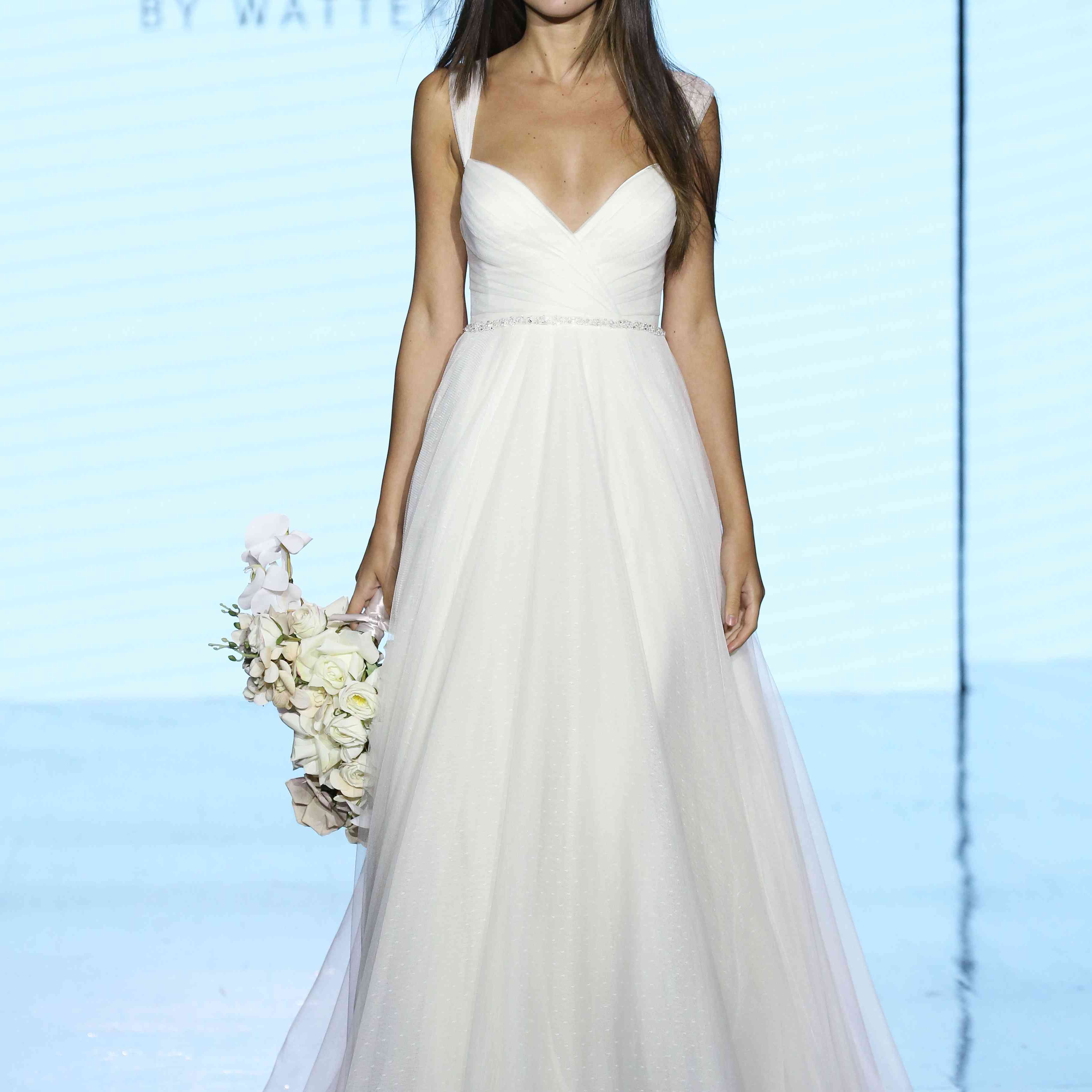 模特身穿薄纱帽袖v领a字长裙，配以珠宝腰带