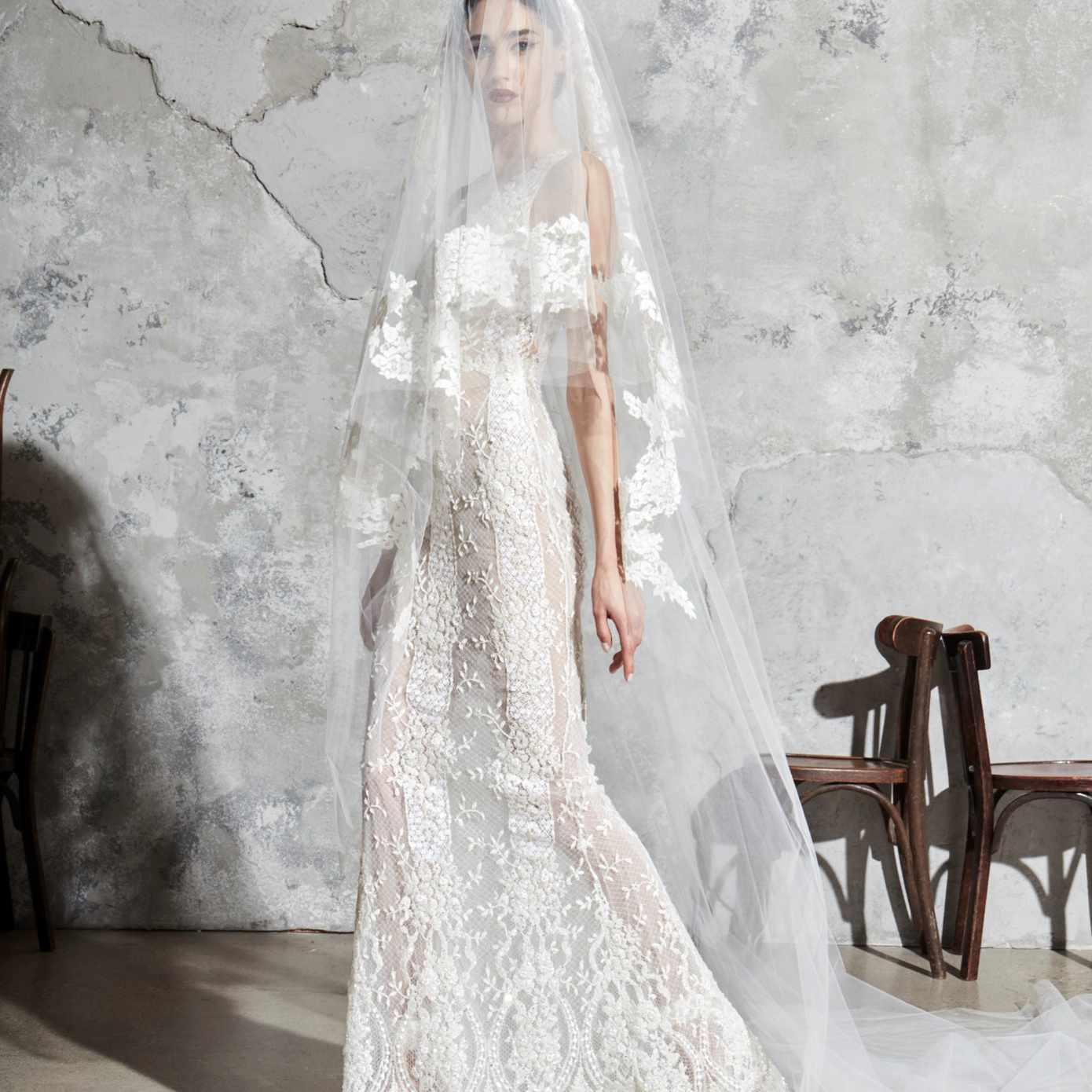 模特身穿无袖全花边薄纱紧身连衣裙，配以相配的面纱