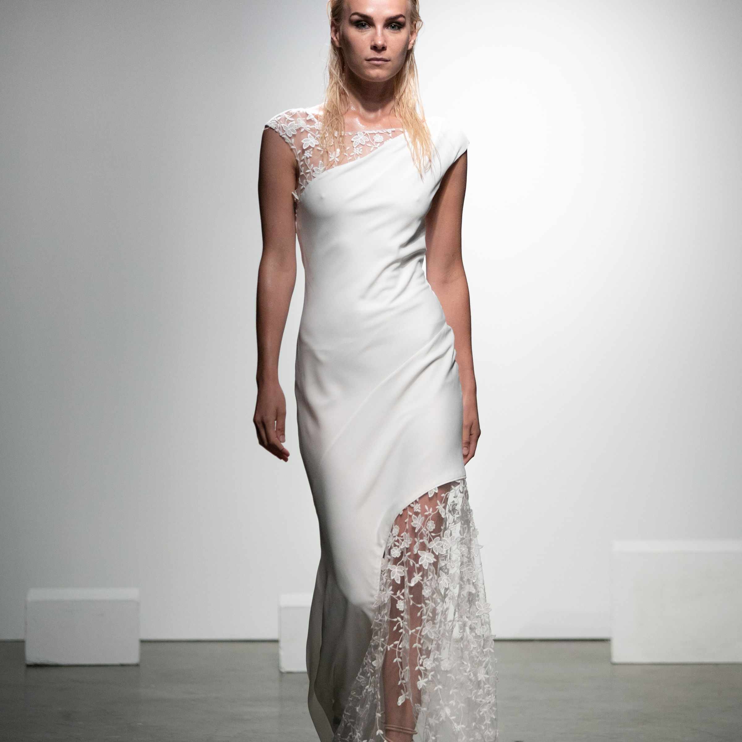 模特身穿不对称绉绸连衣裙，饰有花朵刺绣的薄纱和帽袖