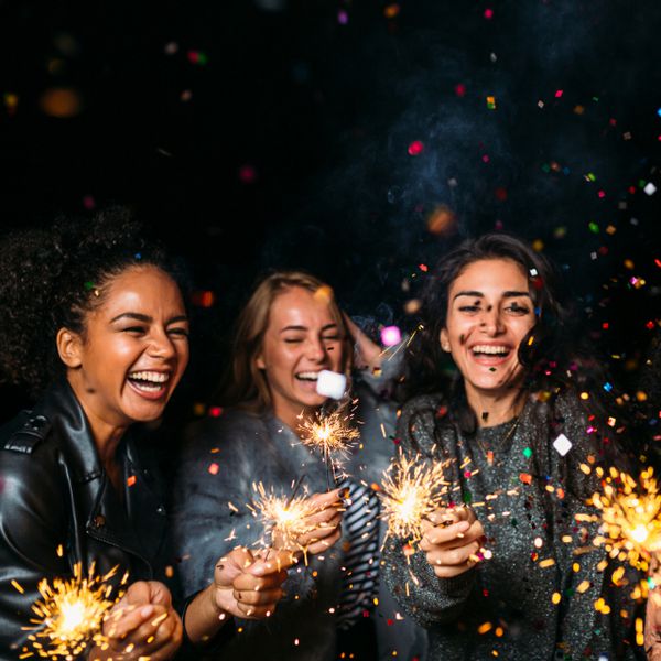 三个女孩笑着拿着有五彩纸屑的烟花