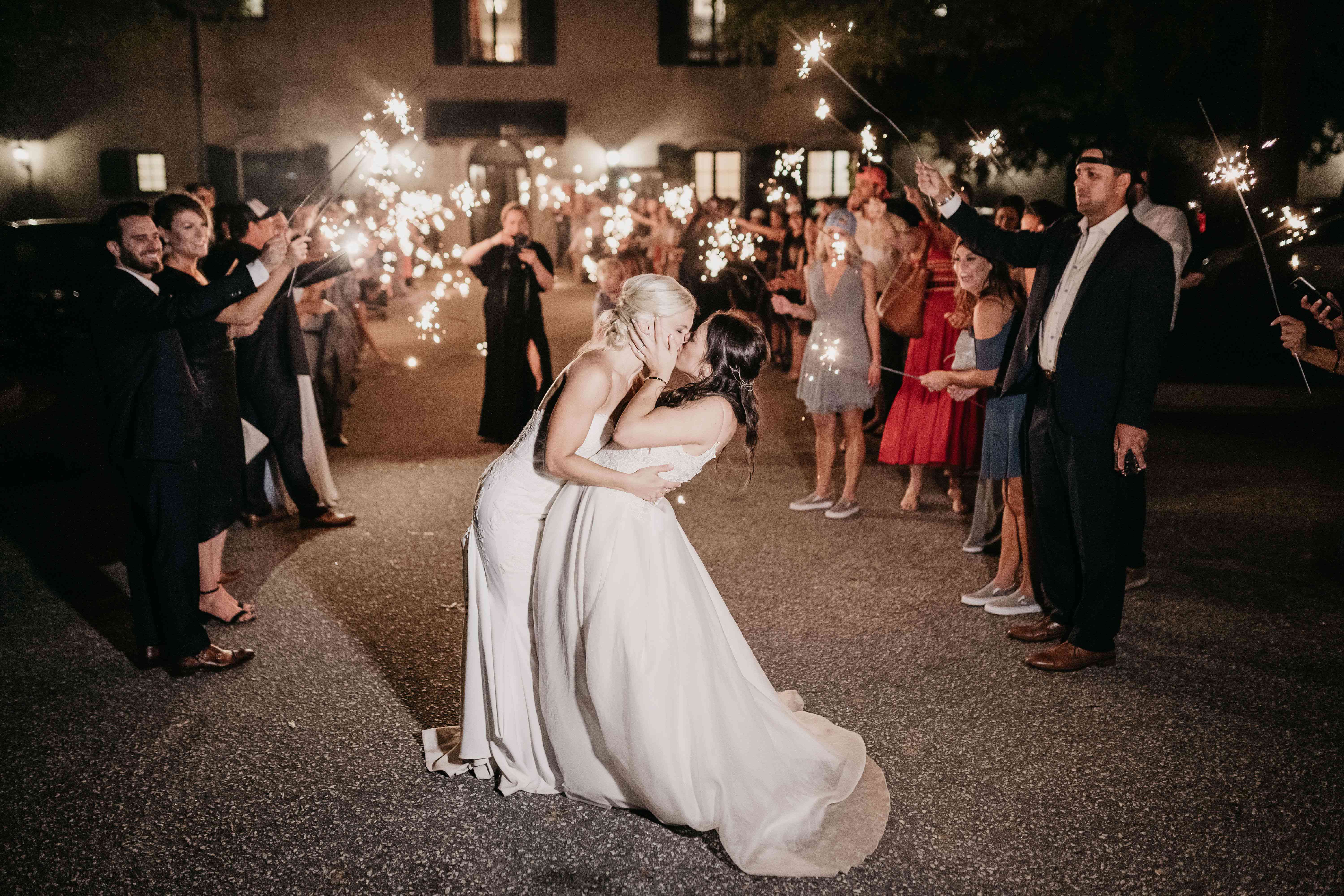 在闪烁发光物婚礼出口期间亲吻的两个新娘