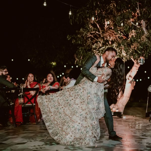 新娘和新郎亲吻，因为他们有他们的第一支舞蹈在一个户外，晚上的婚礼