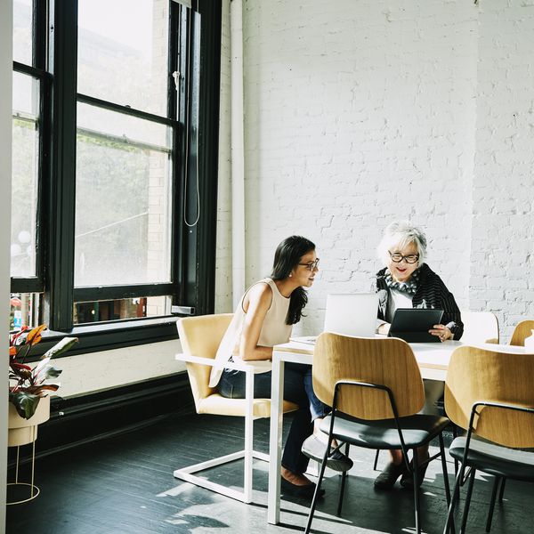在看膝上型计算机和片剂的桌上的两个妇女