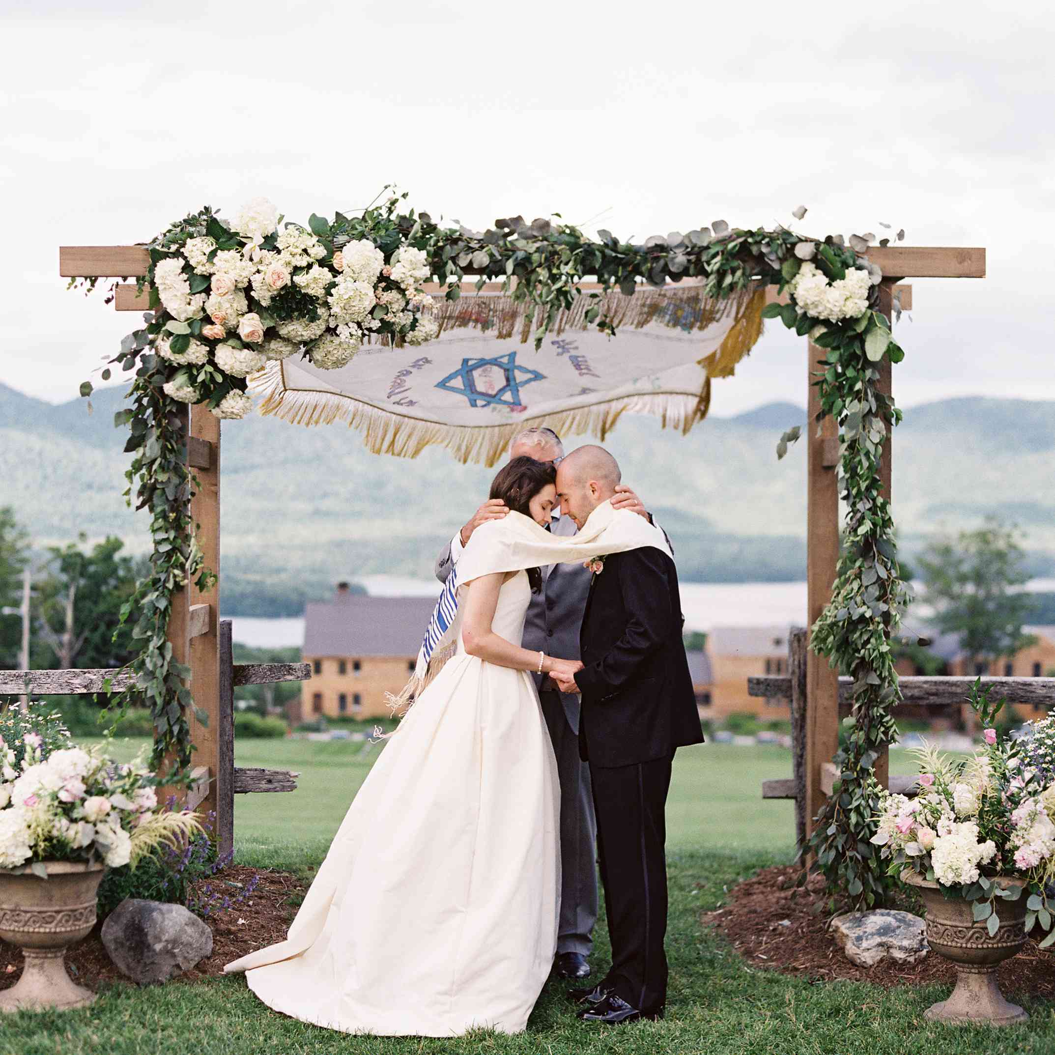 新娘和新郎在他们的婚礼上，站在有以色列国旗的彩花的彩堂前