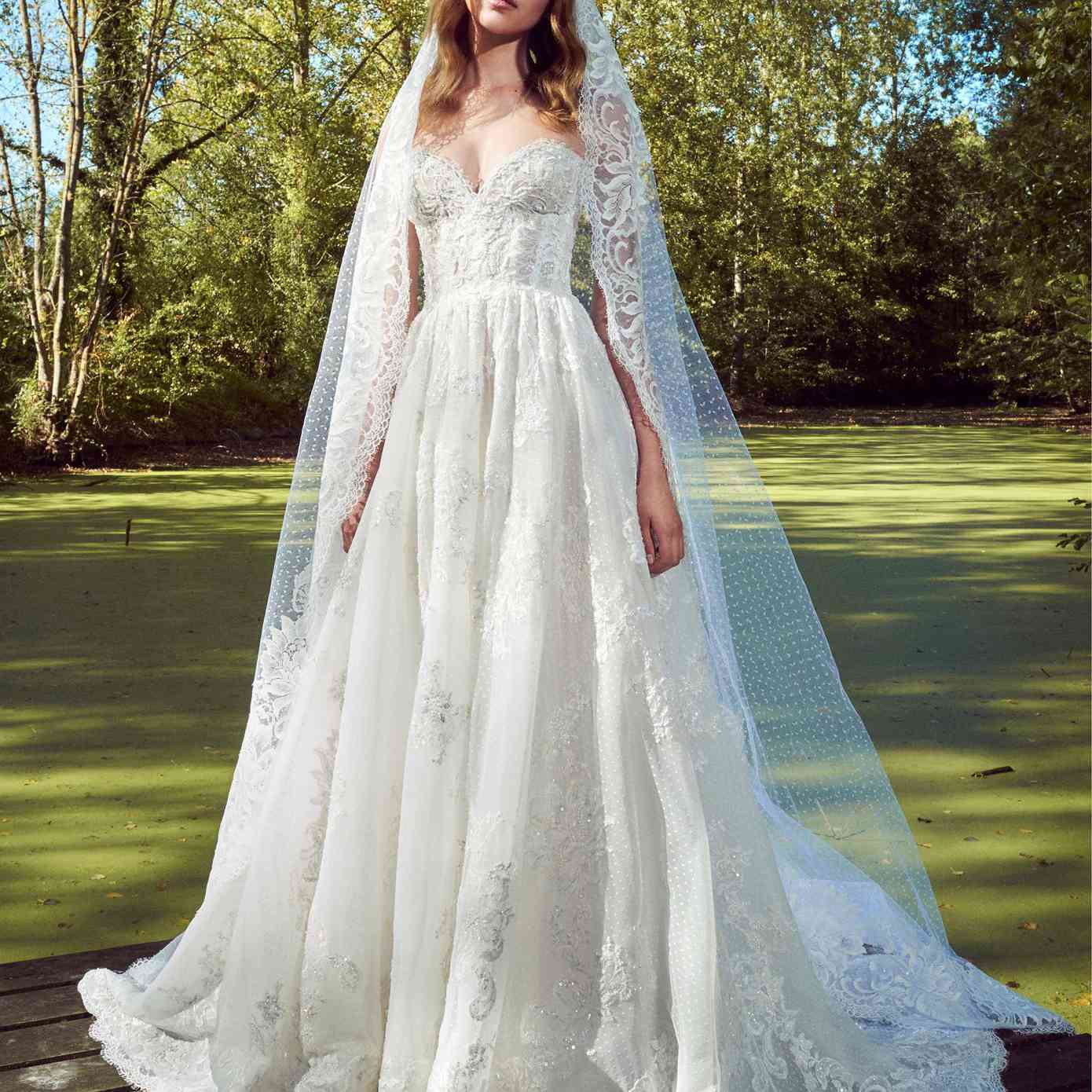 模特在无肩带甜心点薄纱公主礼服与珠蕾丝刺绣和点薄纱花边面纱与睫毛花边装饰