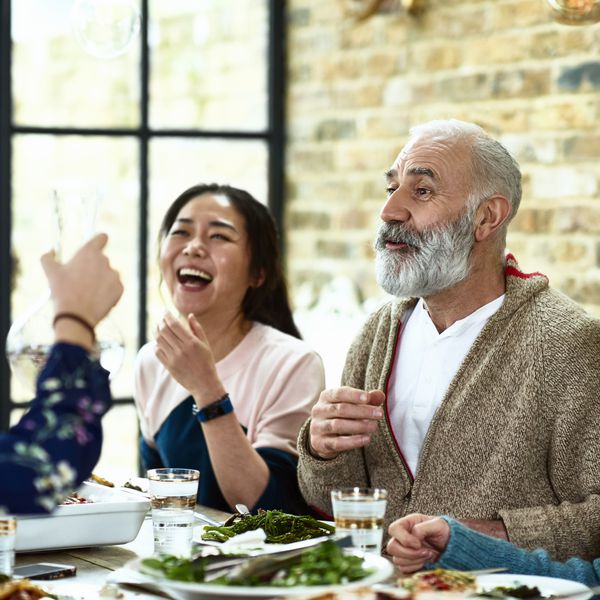 快乐的成熟人讲述在与家庭笑的晚餐的故事