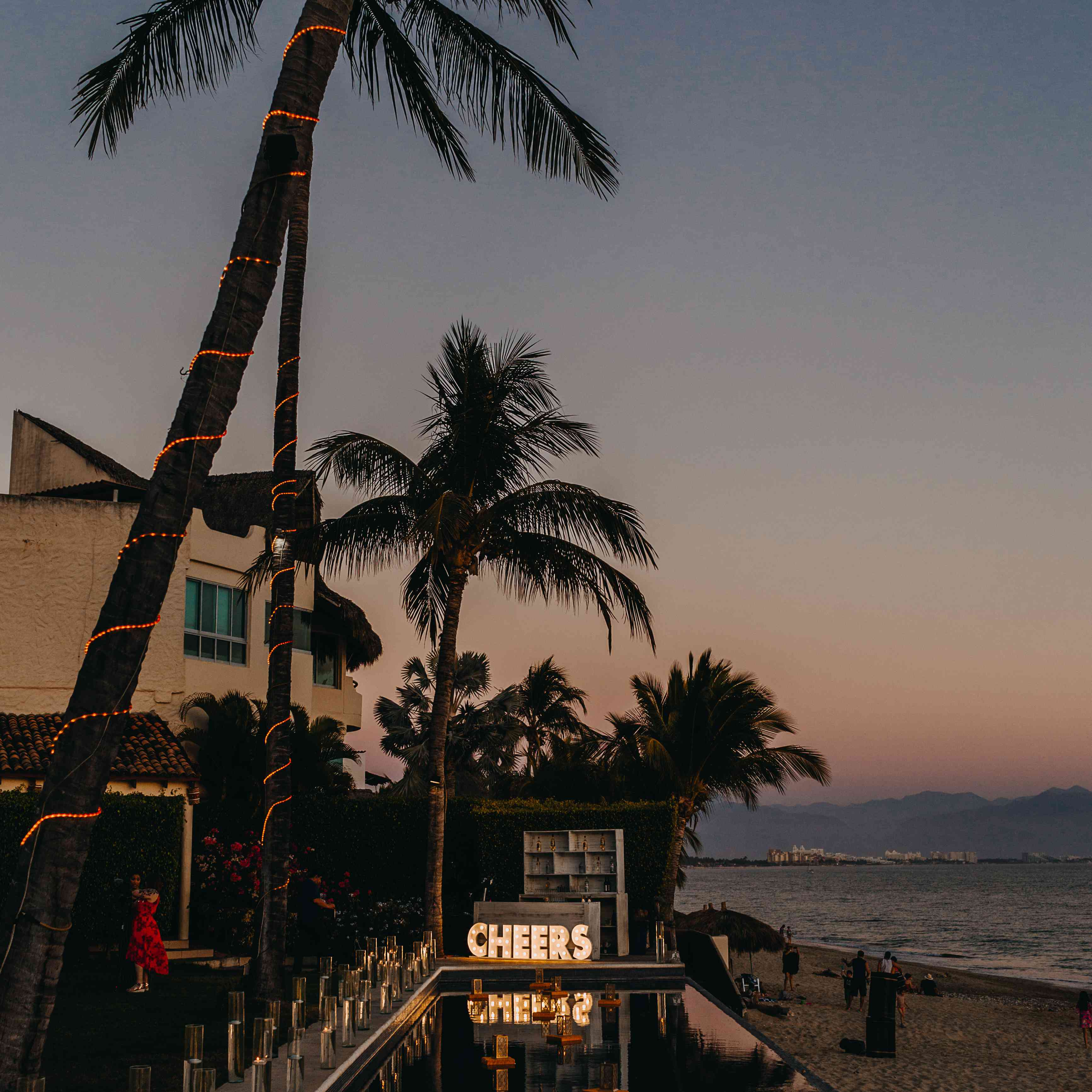 日落无限池强调棕榈树包裹在绳灯