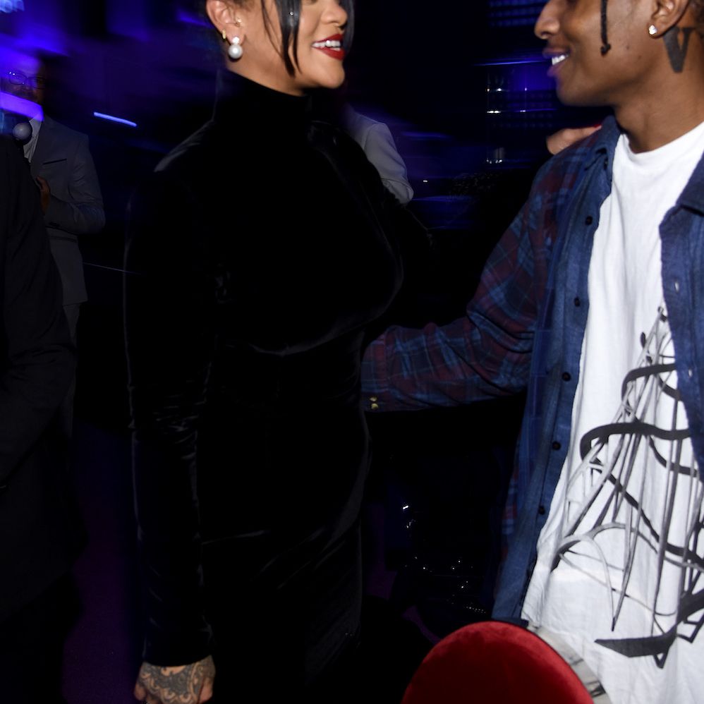 蕾哈娜在朋友抓住她的腰部，戴上一个黑色的合奏，并将一只手放在朋友上的肩膀上。