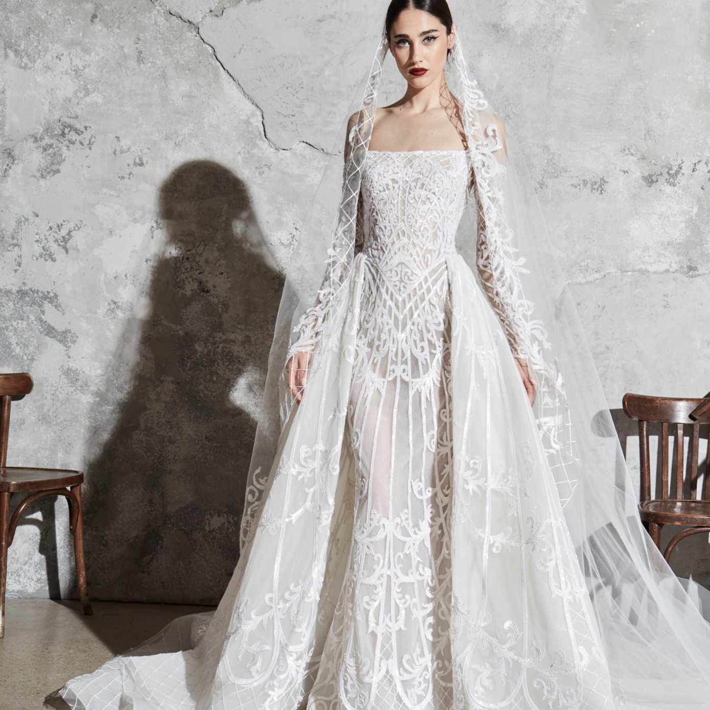 模特在绣花长袖露肩礼服与一个巨大的绣花衬裙和匹配的透明绣花面纱