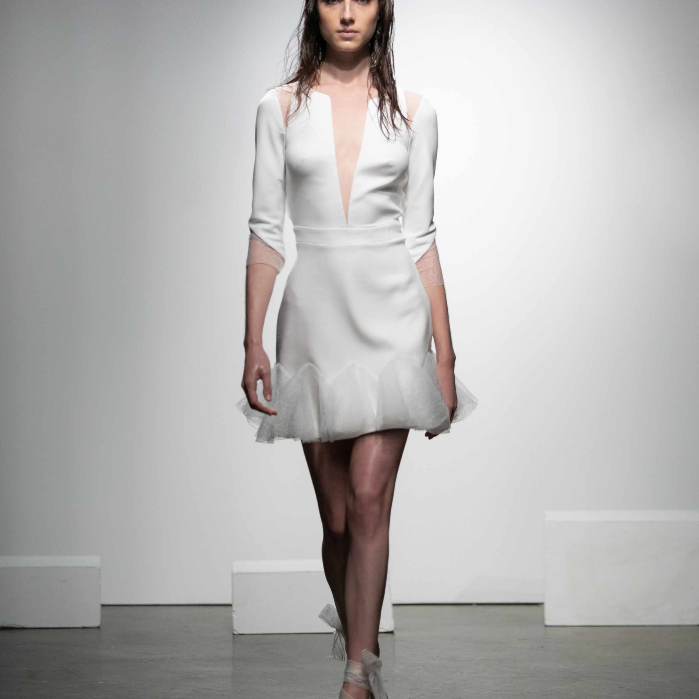 模特穿着四分之一袖的绉纱迷你裙，有低胸领口和鱼网薄纱花边