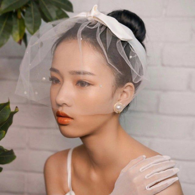 戴圆圈鸟笼面纱的亚裔新娘与弓头饰带