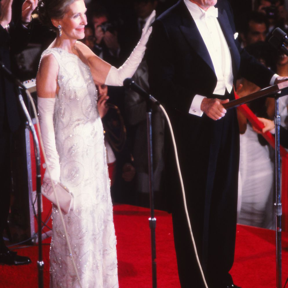 南希·里根(Nancy Reagan)身穿飘逸的长裙，手搭在丈夫的肩膀上，戴着及肘长的手套