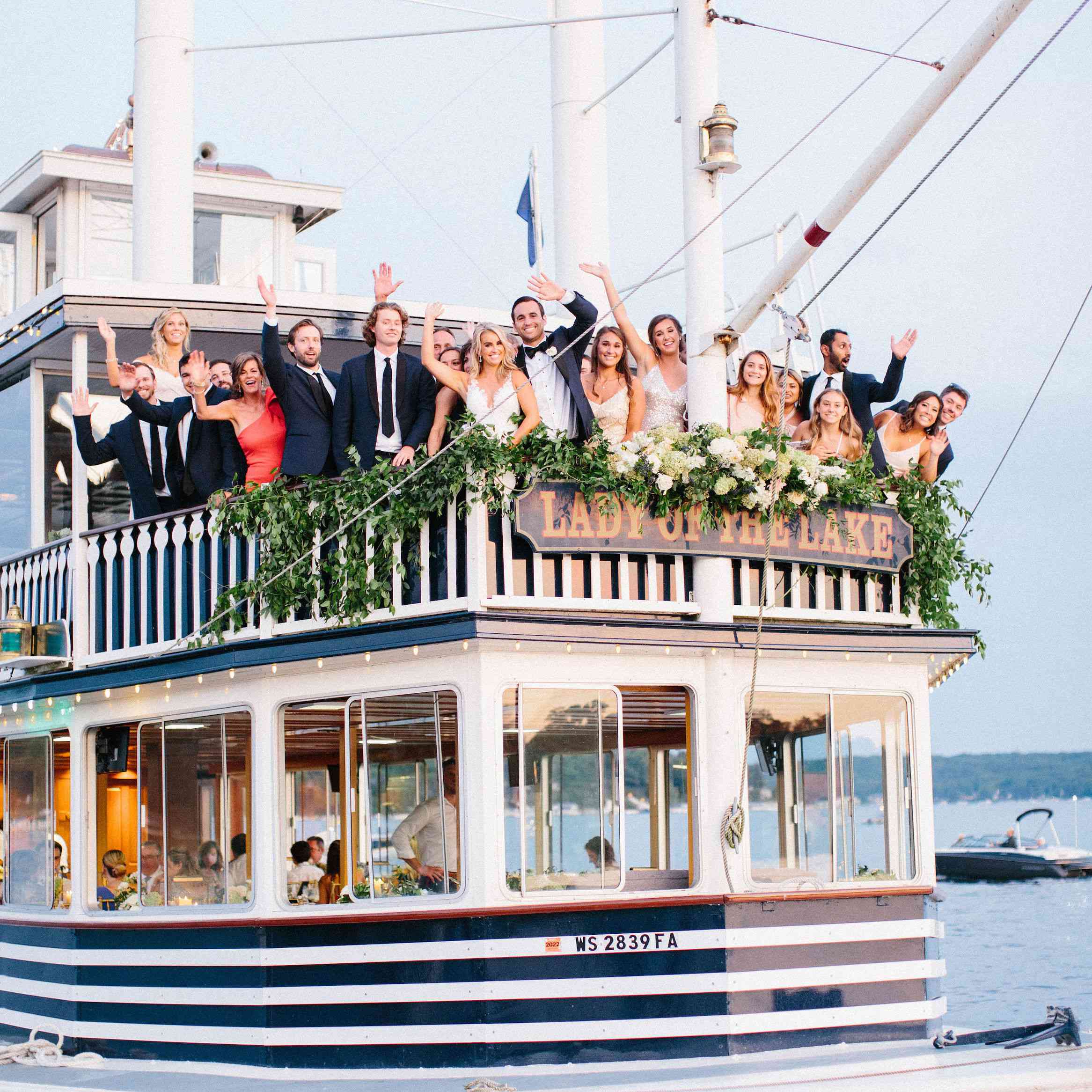 婚礼派对在湖上的女士甲板上招手