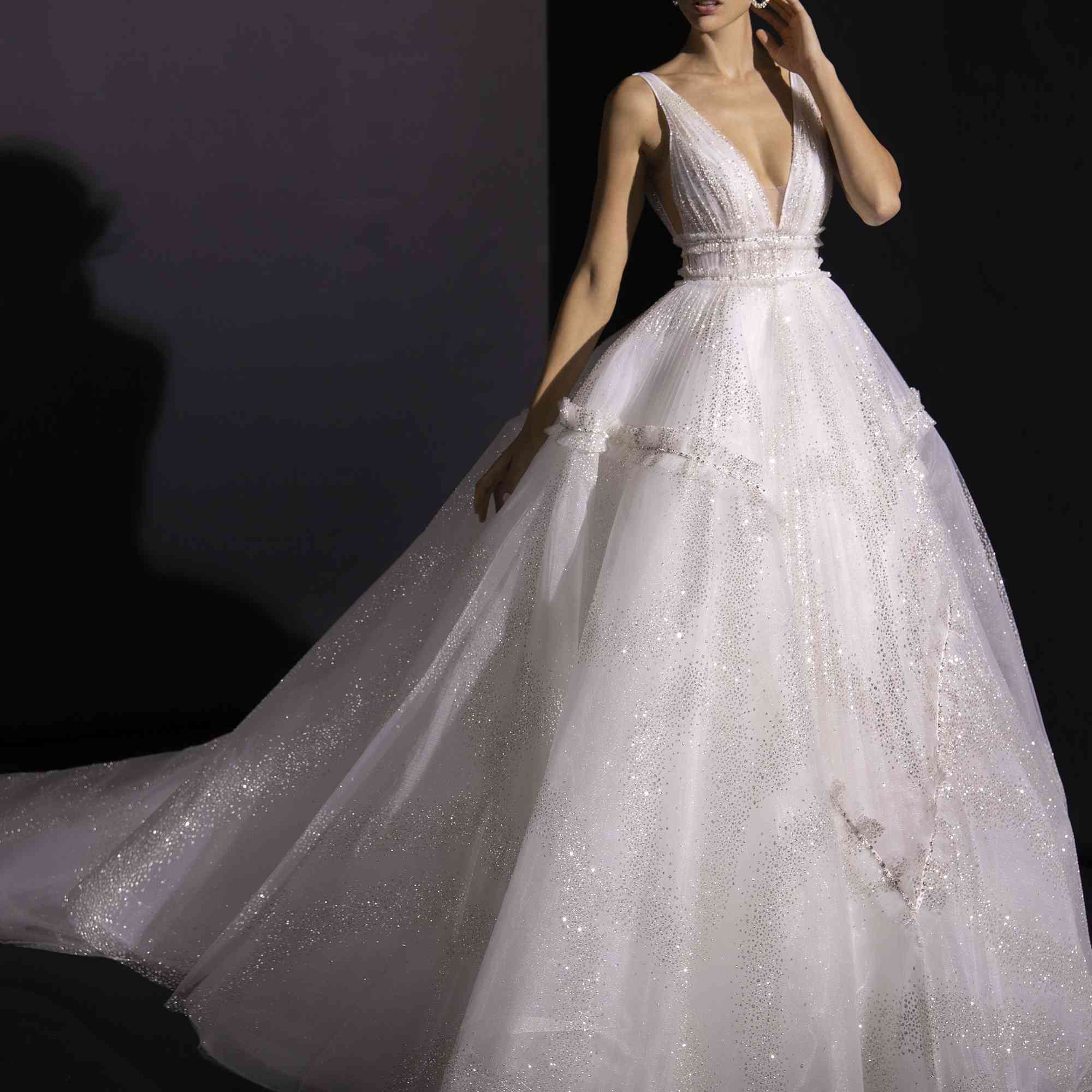 模特身着蓬松的闪光薄纱礼服，深V领