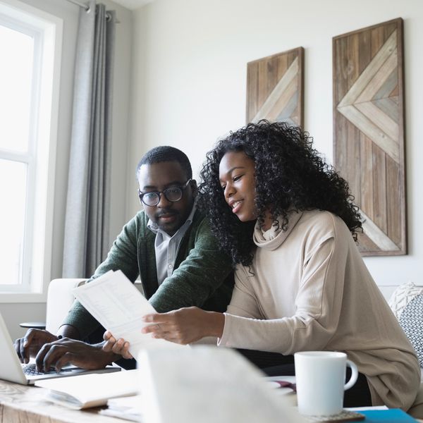 研究在一台预算的夫妇坐有一台膝上型计算机的客厅沙发在咖啡桌上“class=