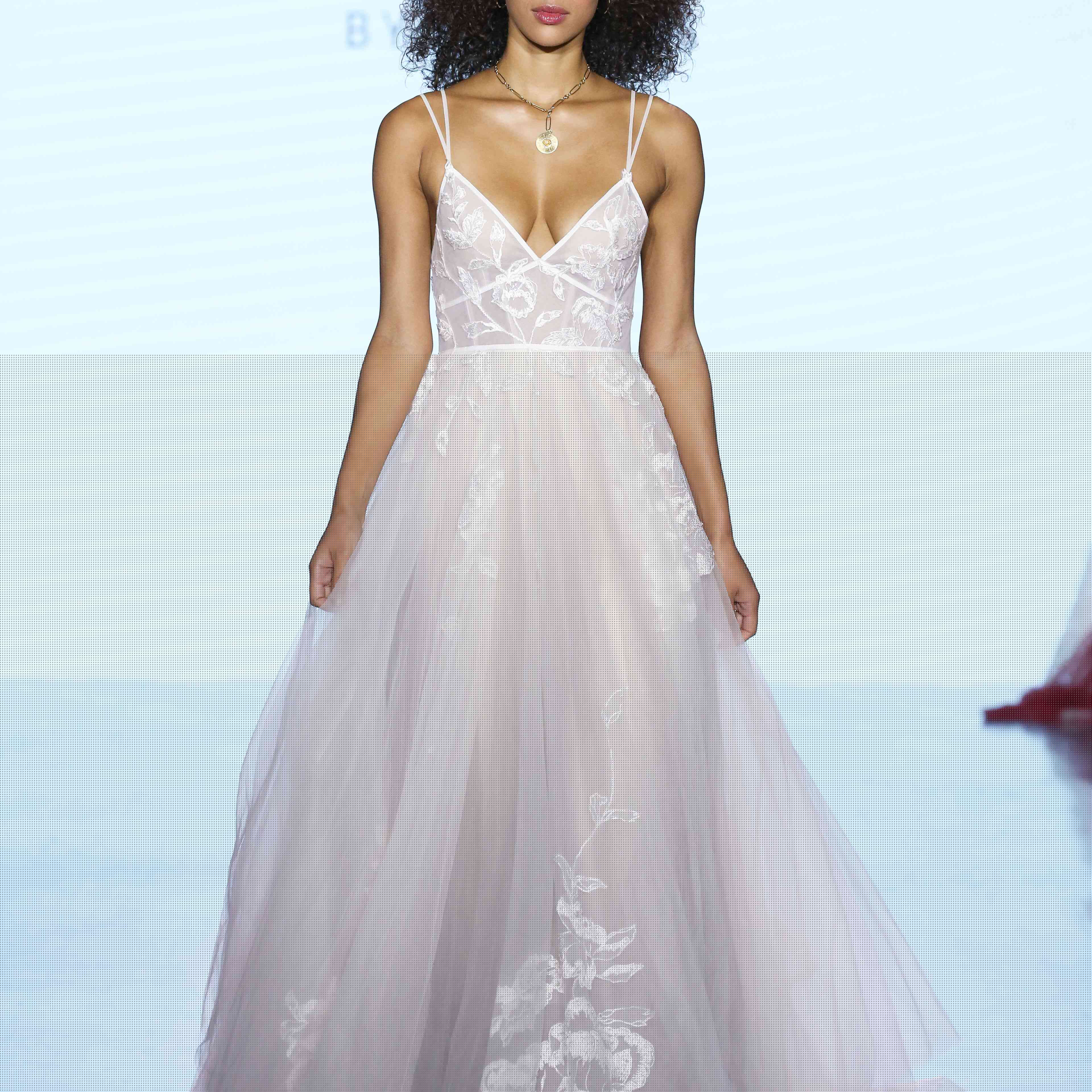 薄纱婚纱的模型与花卉花边绣花，v领绣花，和双重意粉肩带