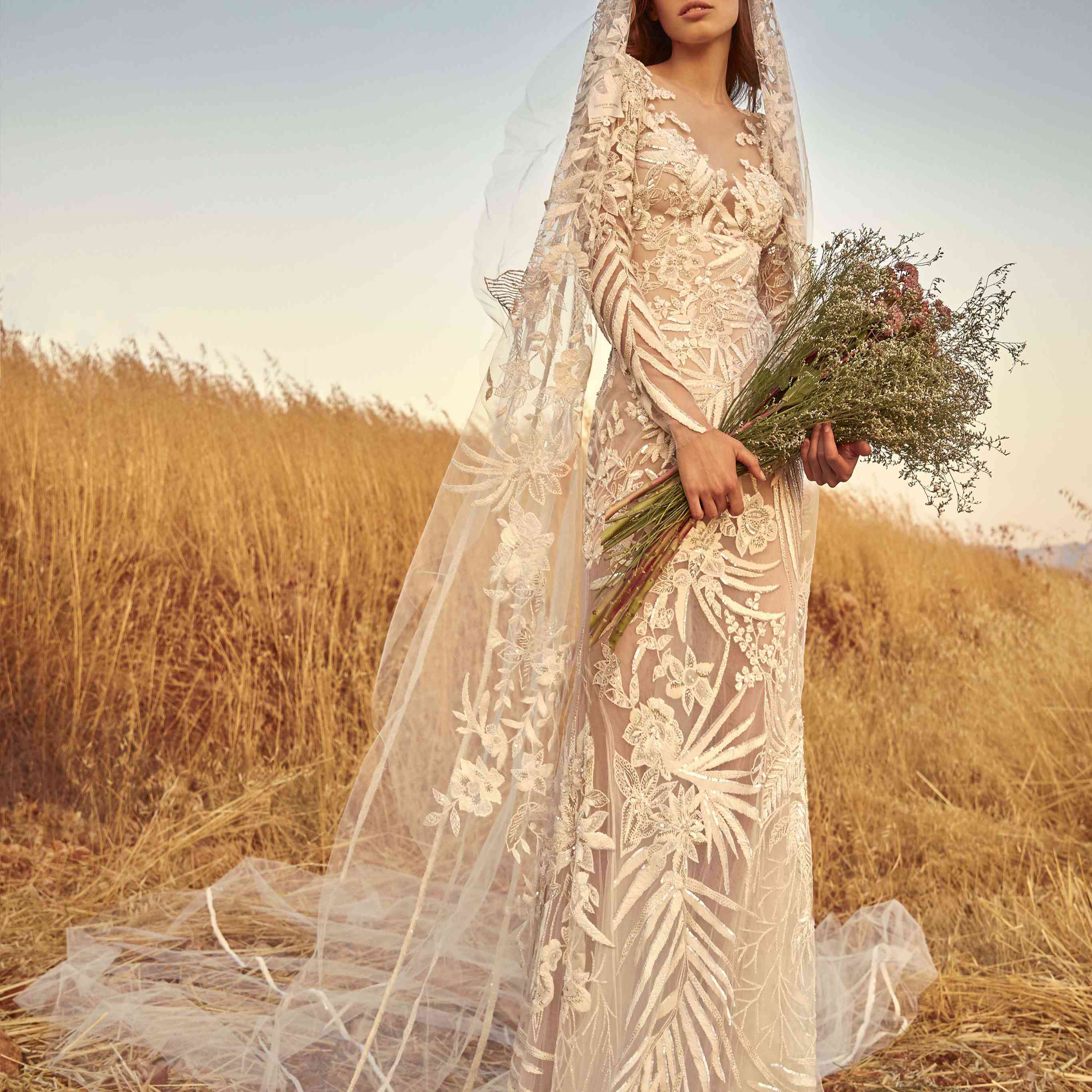 型号拟合完全刺绣的灰白色长袖连衣裙，带有匹配的面纱