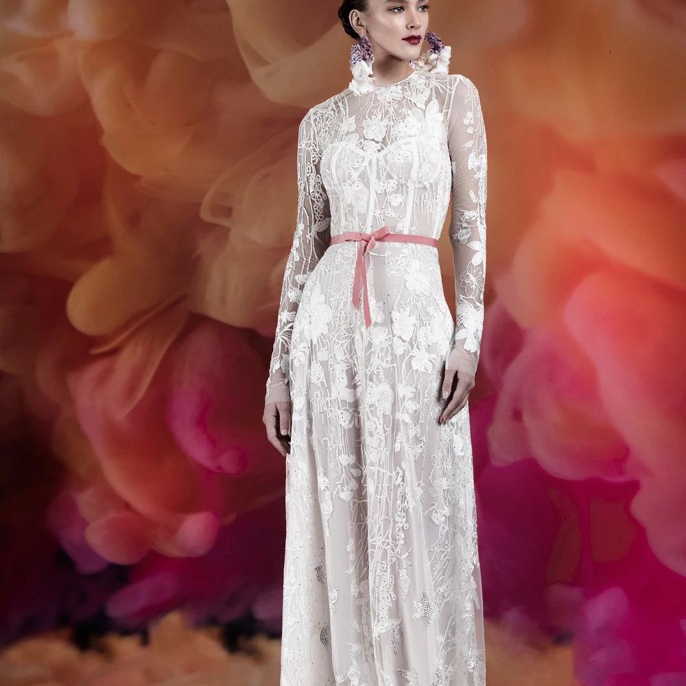 模特在长袖刺绣花边礼服与粉红色的腰带