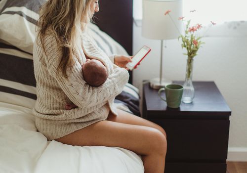 女子坐在床上抱着一个新生