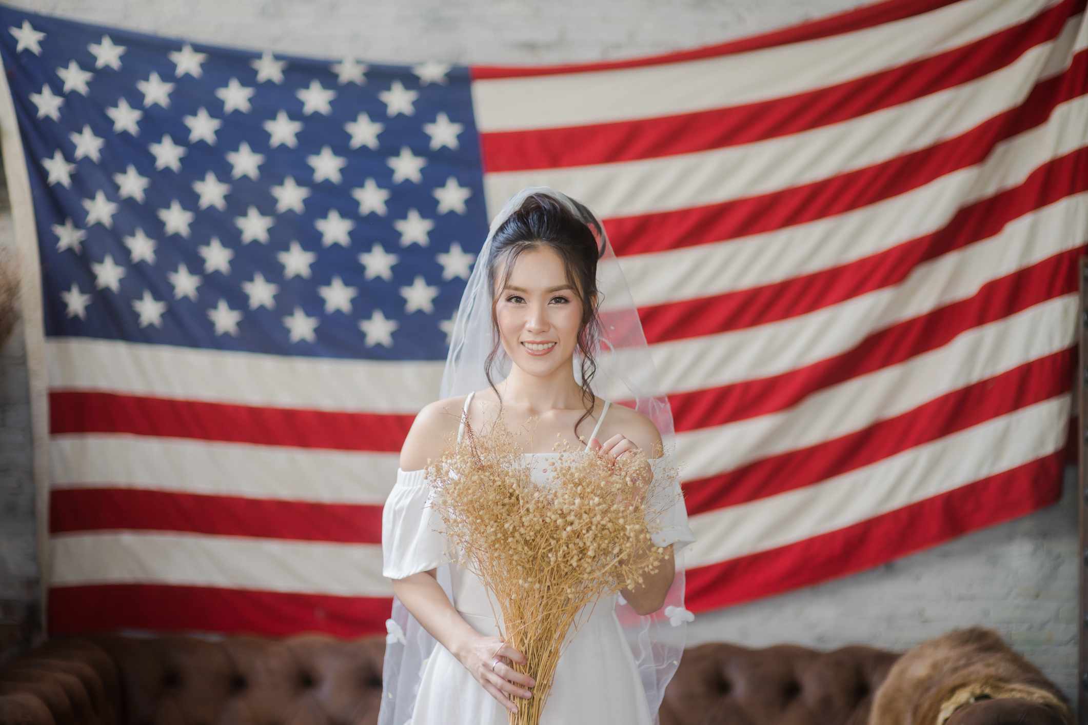 新娘站在美国国旗前“class=