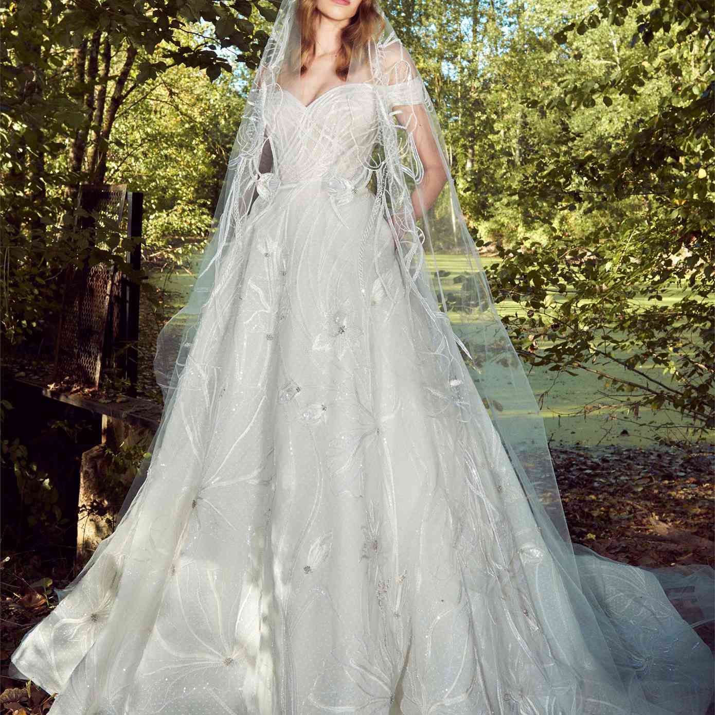 模特在露肩甜心点薄纱舞会礼服与银珠刺绣和裙子口袋与匹配面纱