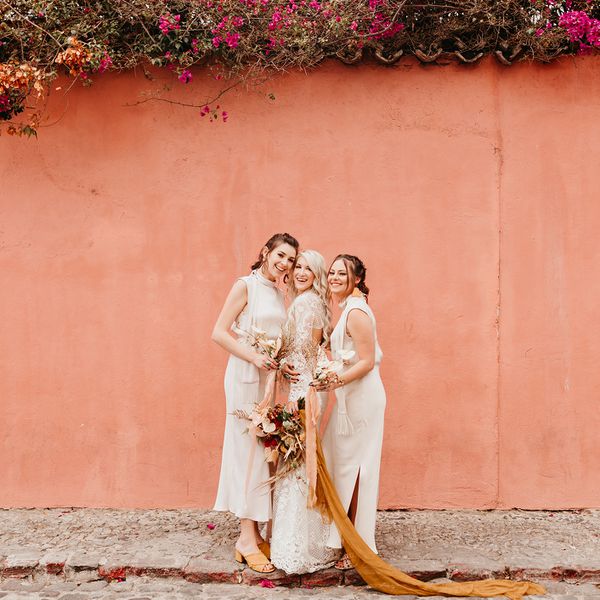 新娘和伴娘在粉红色的墙前摆姿势