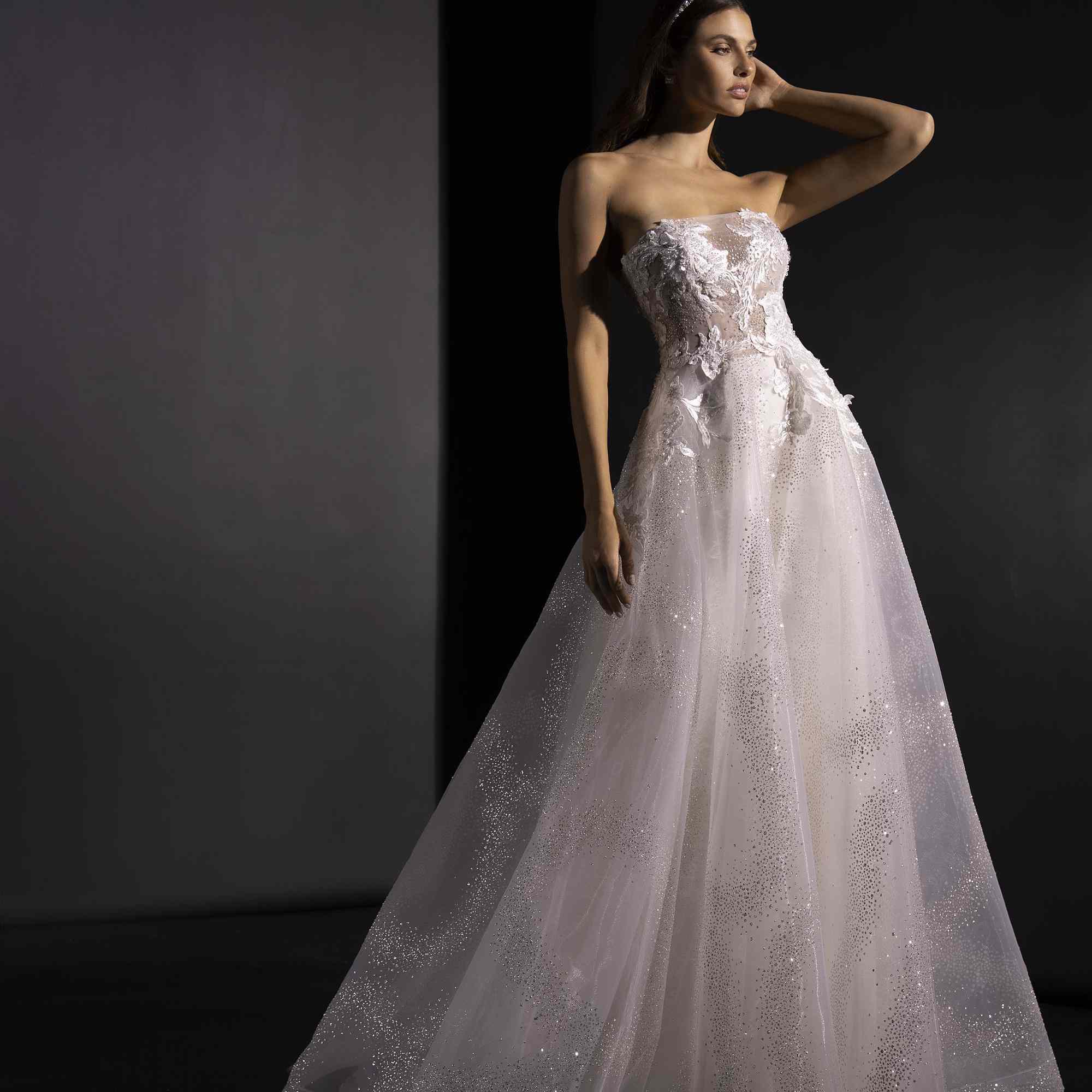 模特身穿无肩带薄纱长礼服，点缀着闪闪发光的花朵