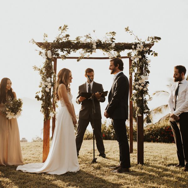 新娘和新郎在婚礼党和麦克风主祭阅读祭坛前