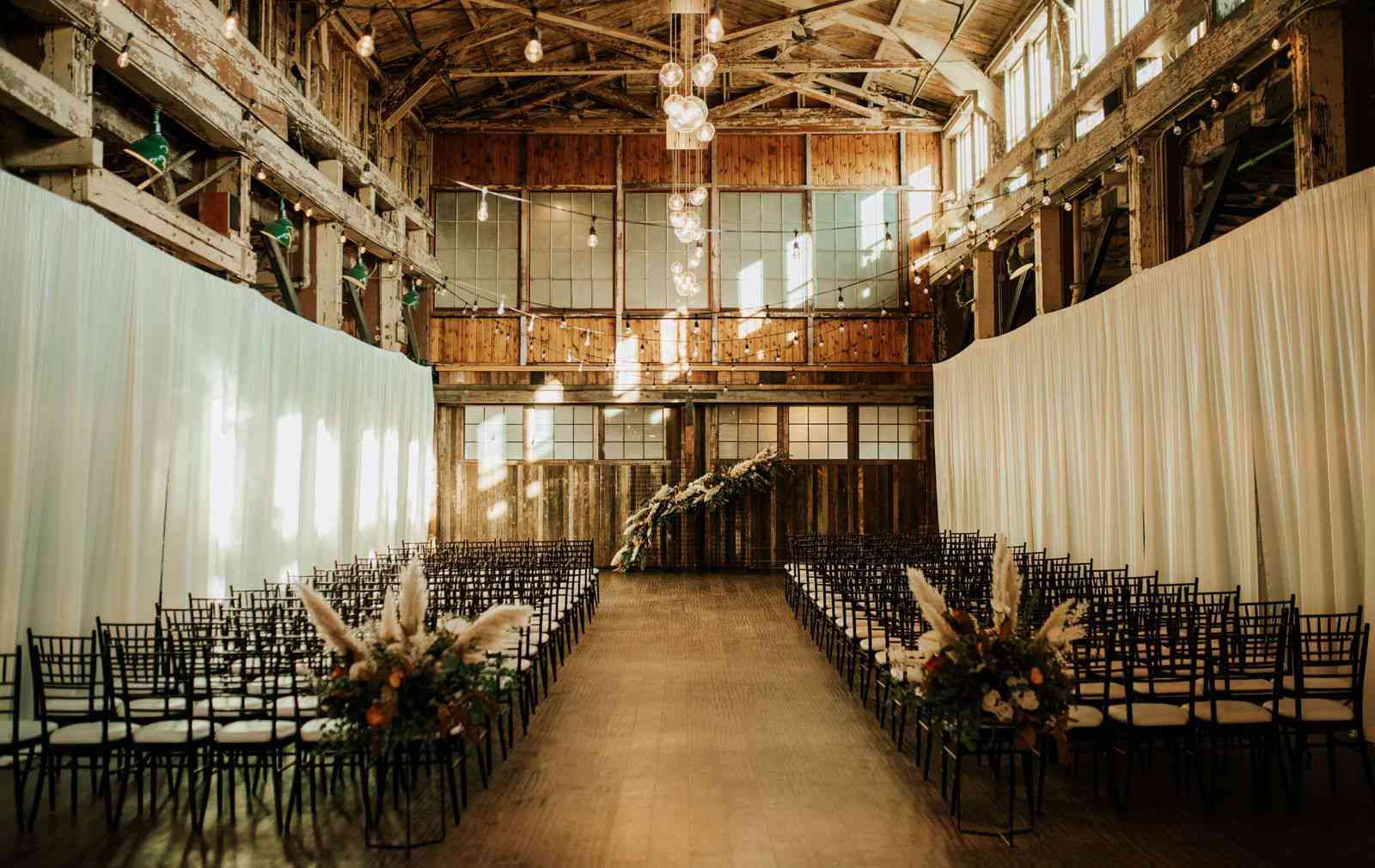 一场室内仪式，在过道的开始放置花卉装置，以配合拱门背景