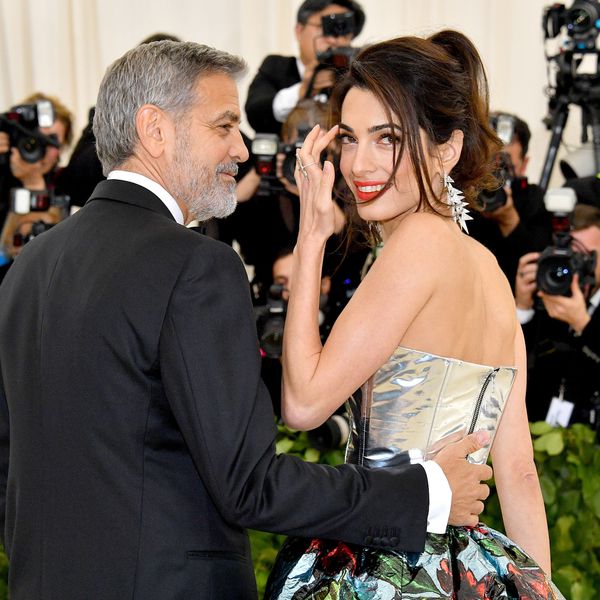 George Clooney手伸向小妻子Amal的背部时,她笑一笑并刷下她脸上一串毛