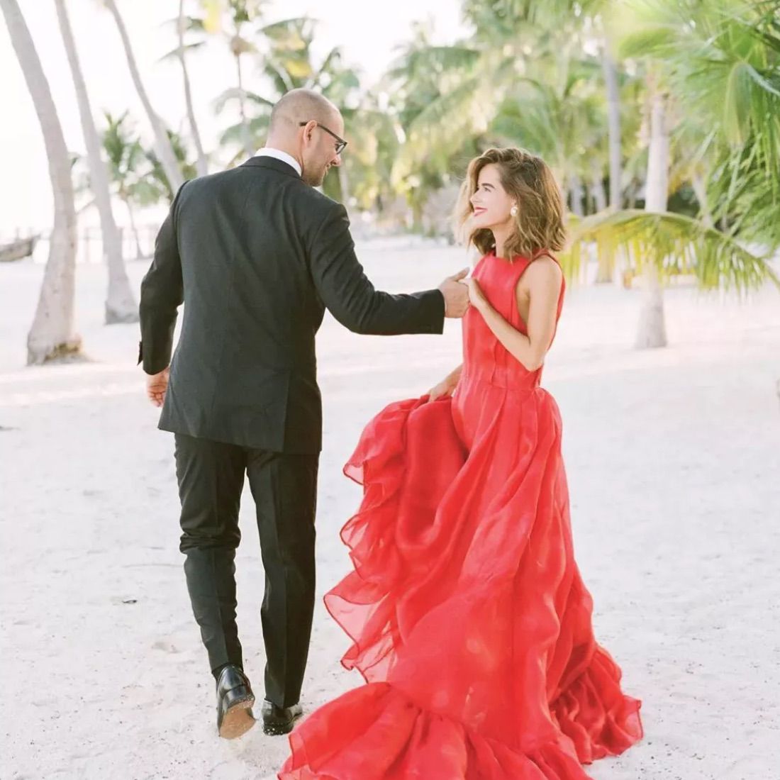 身着红色礼服的新娘和新郎在海滩上